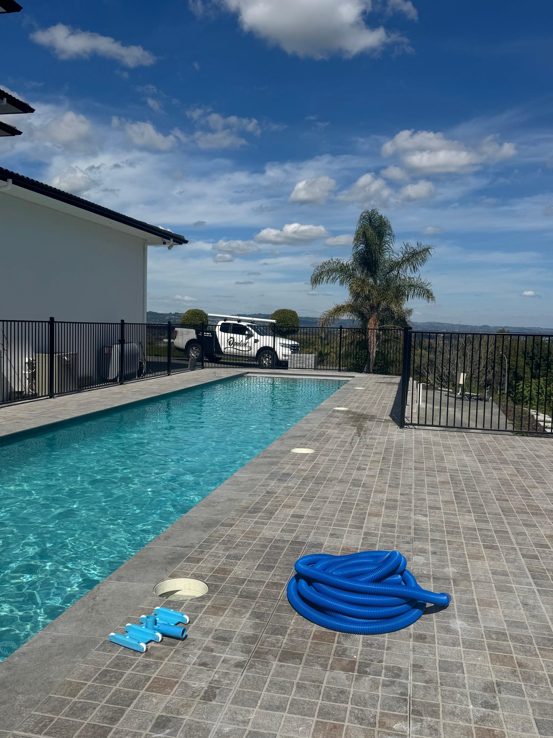 Rectangular pool on a hilltop Auckland property with panoramic views, freshly cleaned with equipment laid out on the deck
